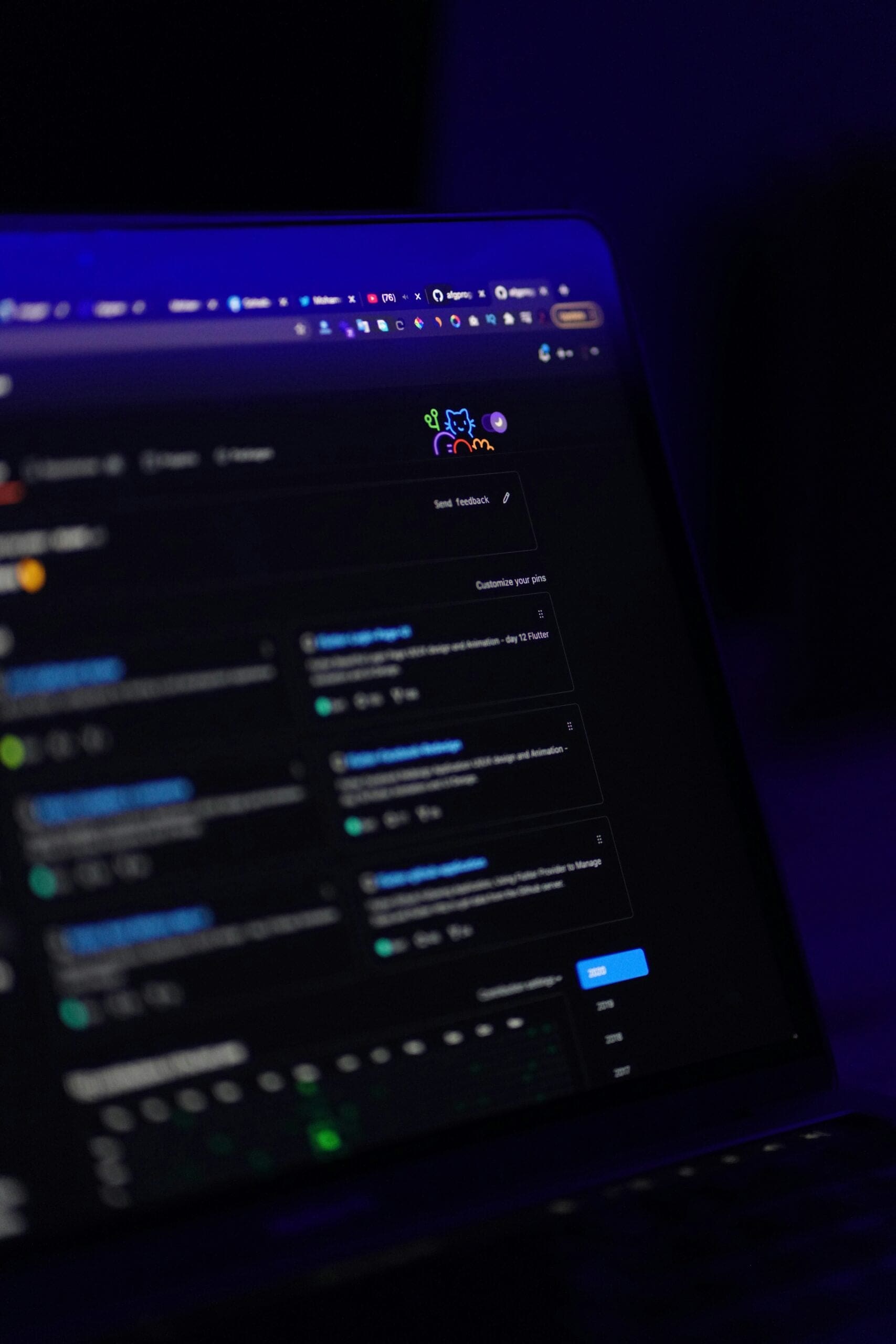A laptop screen displaying a dark-themed website or application interface with various text boxes, icons, and navigation elements, set against a dark background with blue lighting.