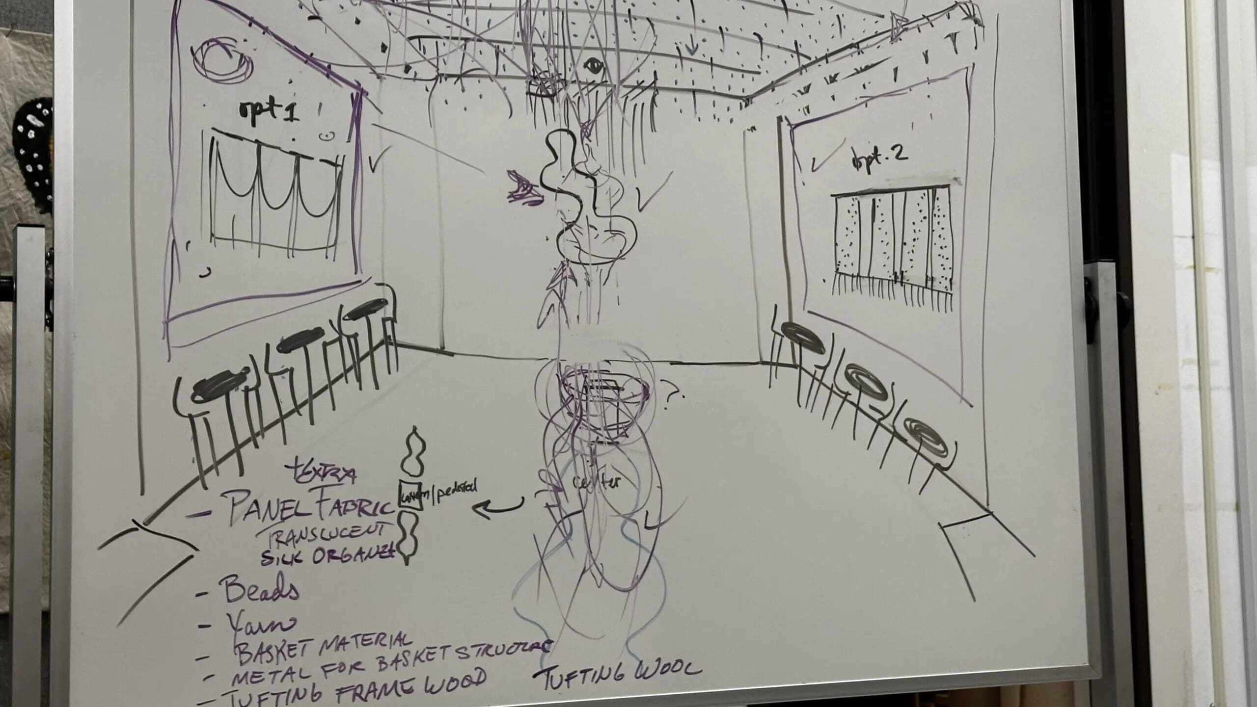 A whiteboard sketch of a room with two walls labeled opt 1 and opt 2, each featuring framed art and chairs. Notes list materials like panel fabric, beads, yarn, and wood. Scribbles and arrows annotate the design.