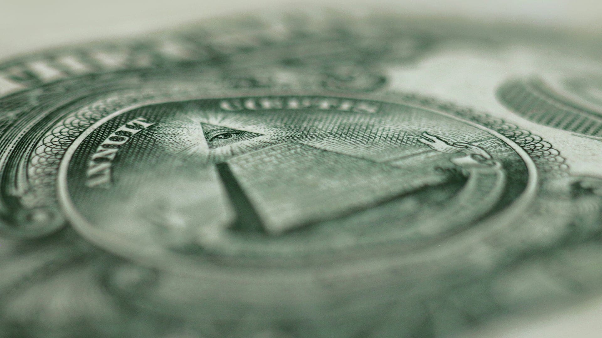 Close-up of the Great Seal on a U.S. one dollar bill, showing the Eye of Providence atop a pyramid with the Latin words Annuit Coeptis above and Novus Ordo Seclorum below.